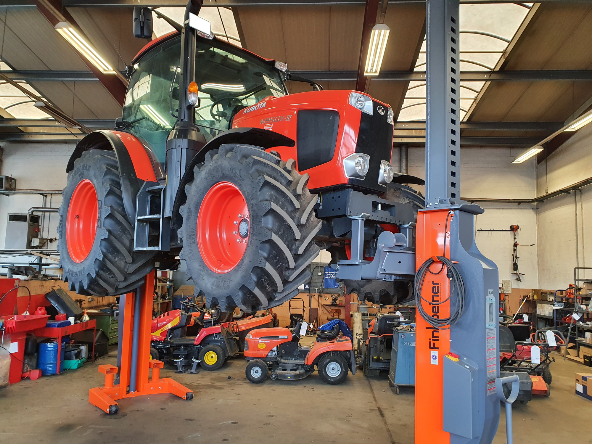 A Kubota tractor is lifted at front and at back with two mobile columns.