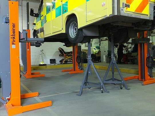 One axle of the vehicle is lowered onto portable support stands, for free access to the wheels